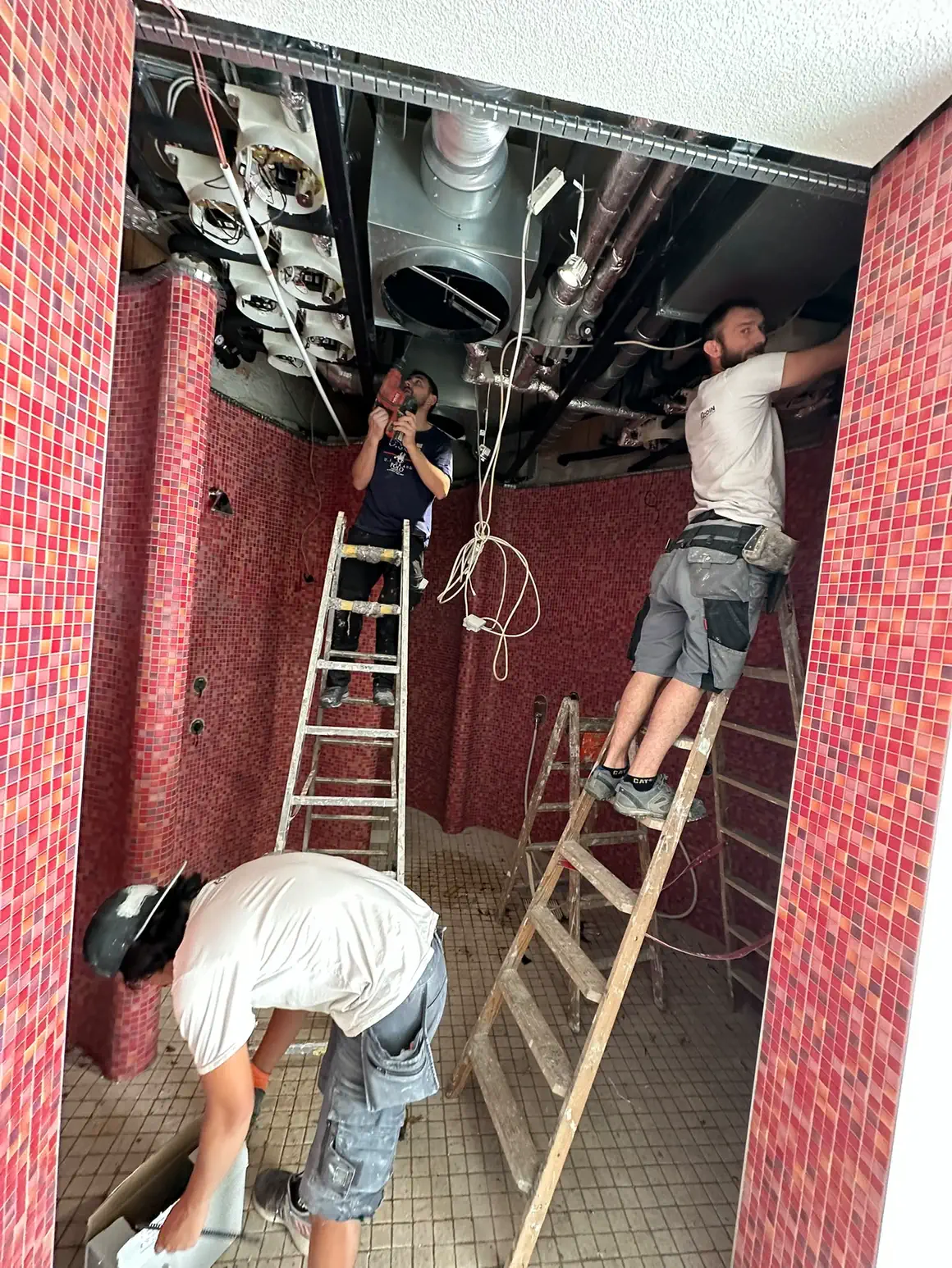 Drei Mitarbeiter bei der Montage an der geöffneten Decke über dem Mosaikraum