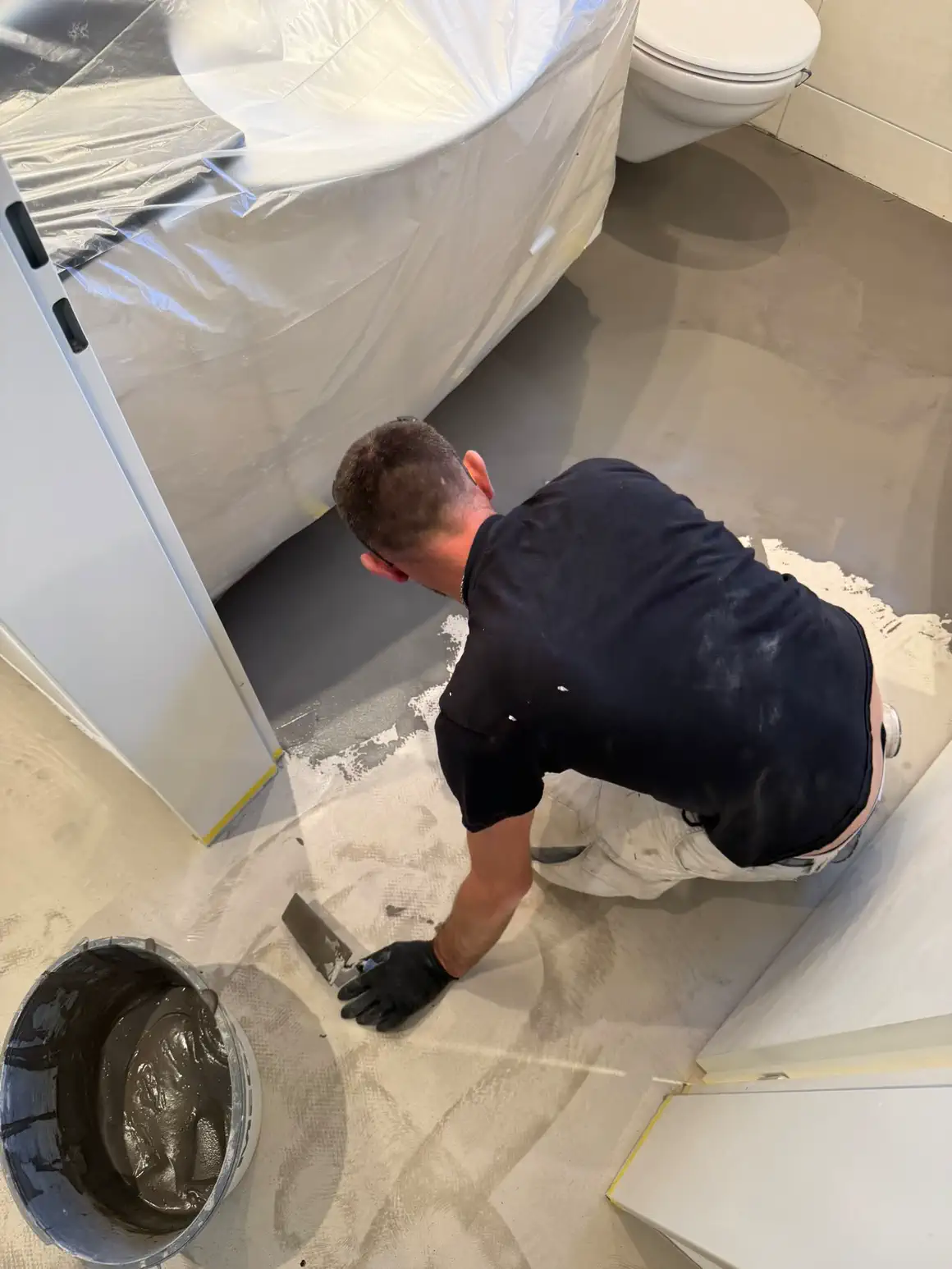 Plattenleger von Bodin Bau beim Spachteln des Badezimmerbodens