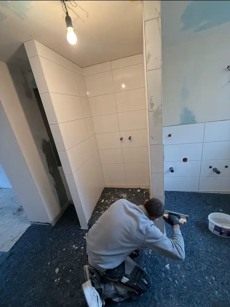 Plattenleger von Bodin Bau beim Setzen der Wandplatten in der neuen Dusche