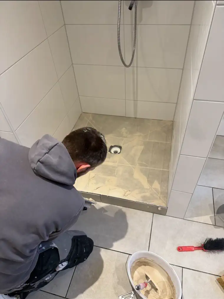 Verfugen des Duschbodens, dessen Platten auf Gefälle zum Punktablauf geschnitten sind