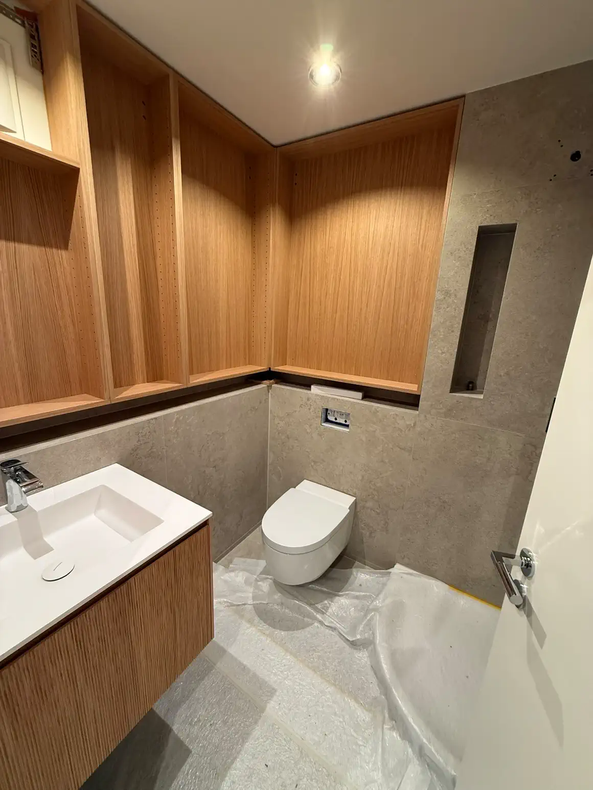 Dasselbe Bad nach dem Umbau: Grossformatplatten in Steinoptik, Einbauschrank in Eiche bis zur Decke, wandhängendes WC und Wandnische