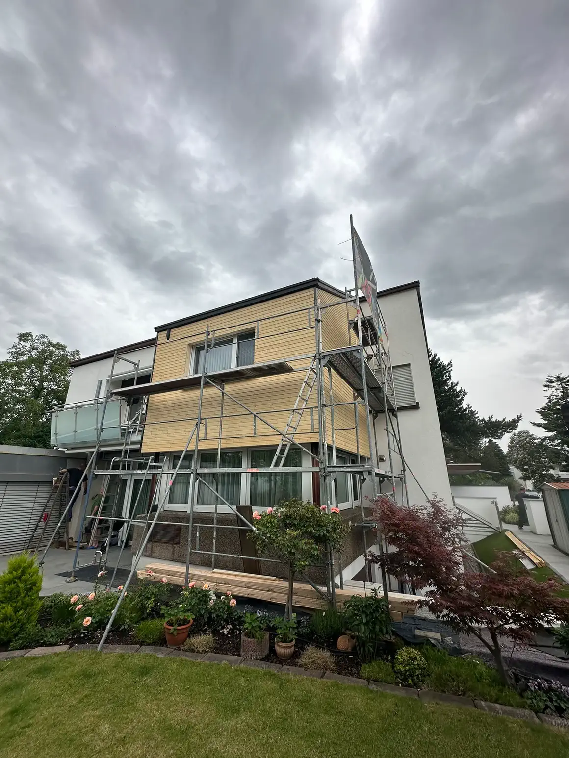 Wohnhaus im Gerüst, das Obergeschoss ist mit neuer Holzschalung belegt